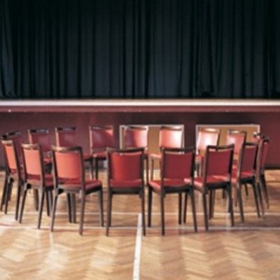 Image of Mary McIntyre's: Aura of Crisis 1998. The photograph shows a ring of empty leather backed chairs arranged in an empty hall.