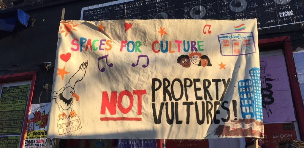 a photograph of a protest banner, with images and text reading Spaces for Culture not Property Vultures'
