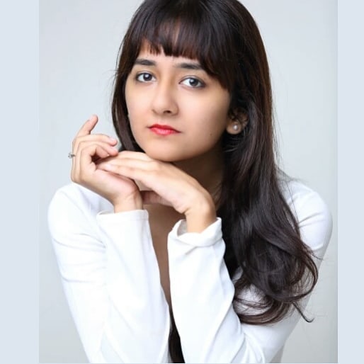 posed portrait photograph of Pranjulaa, resting on elbows, chin rested on hands, against a plain white background