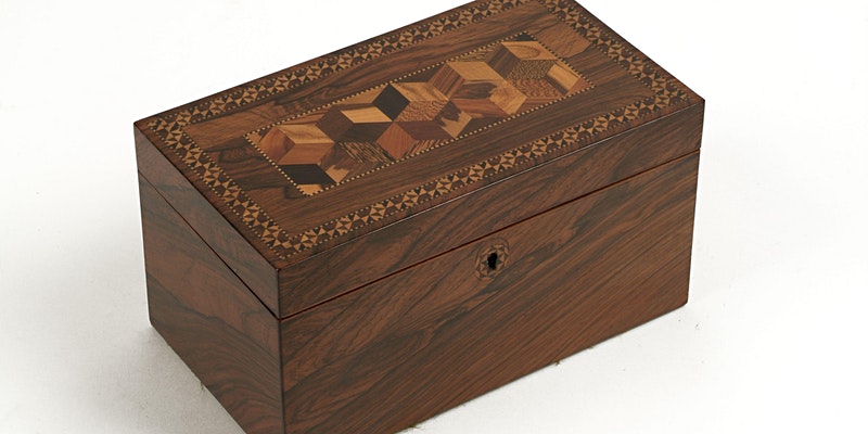 Image of a small, rectangular wooden box with a decorative pattern set into the lid.