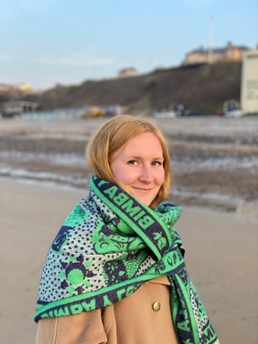 half length portrait photo of Alex in outdoor clothes, standing on beach