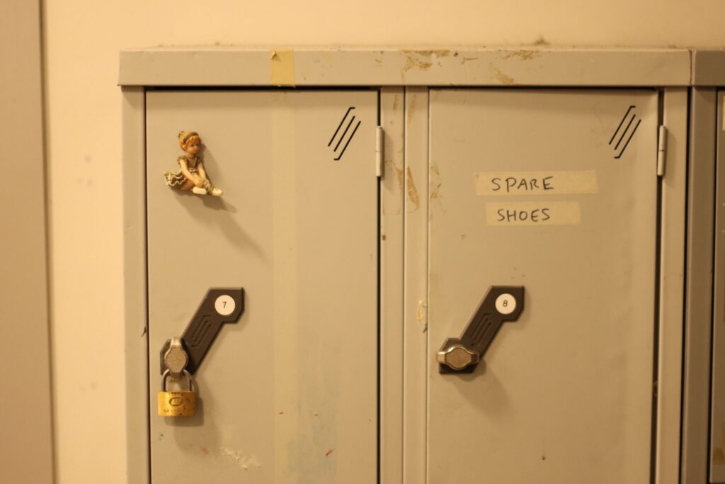 three grey metal lockers. the words 'spare shoes' are written in marker pen on the central locker 