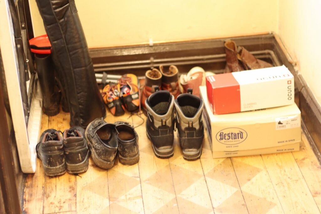 a selection of muddy shoes in the corner of a room