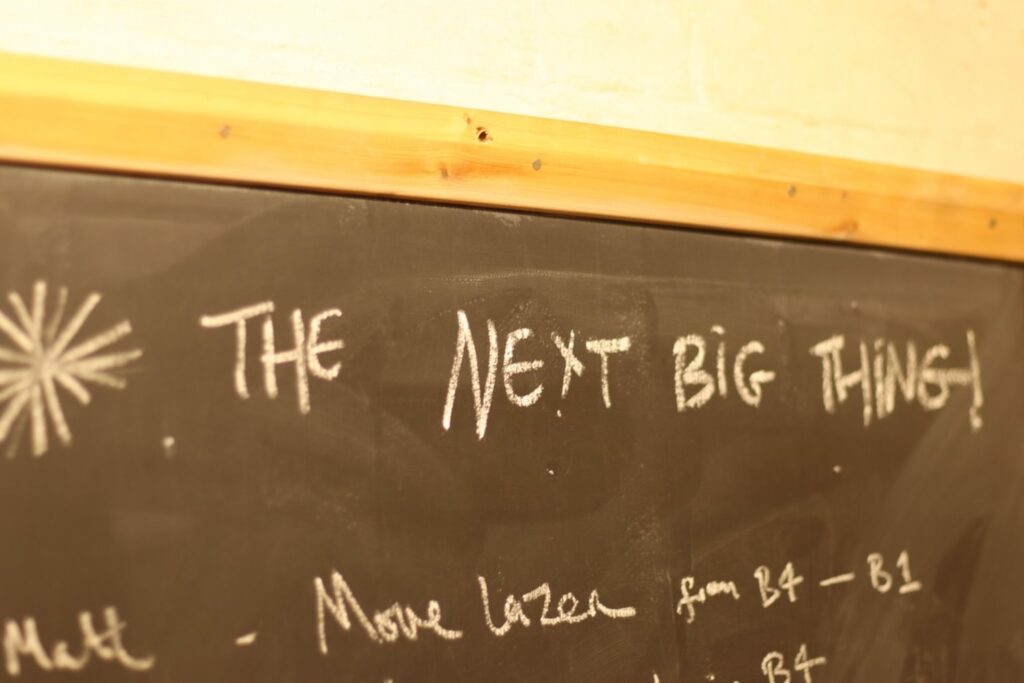 White writing on a black chalkboard reading "the next big thing"