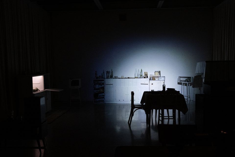 A dark living space, lit by a bright white torchlight pointed directly at the back wall.